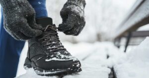 Person som knyter sko i i vinterkulde.